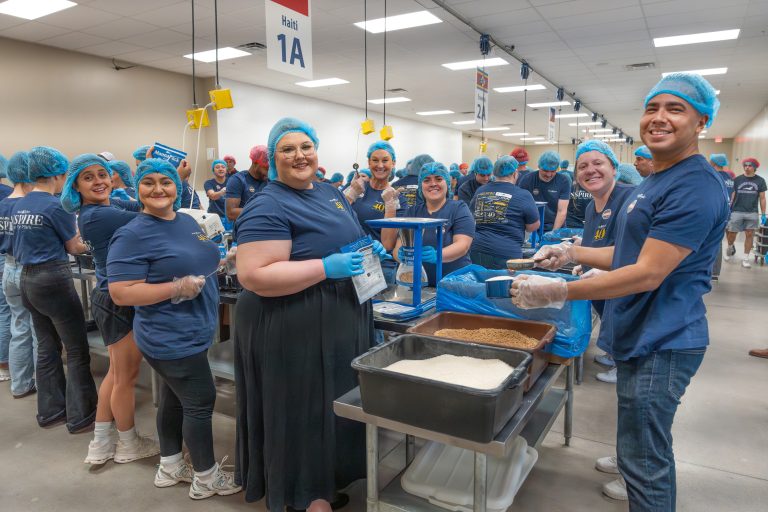 Volunteers from Mark Taylor packing food in assembly line.