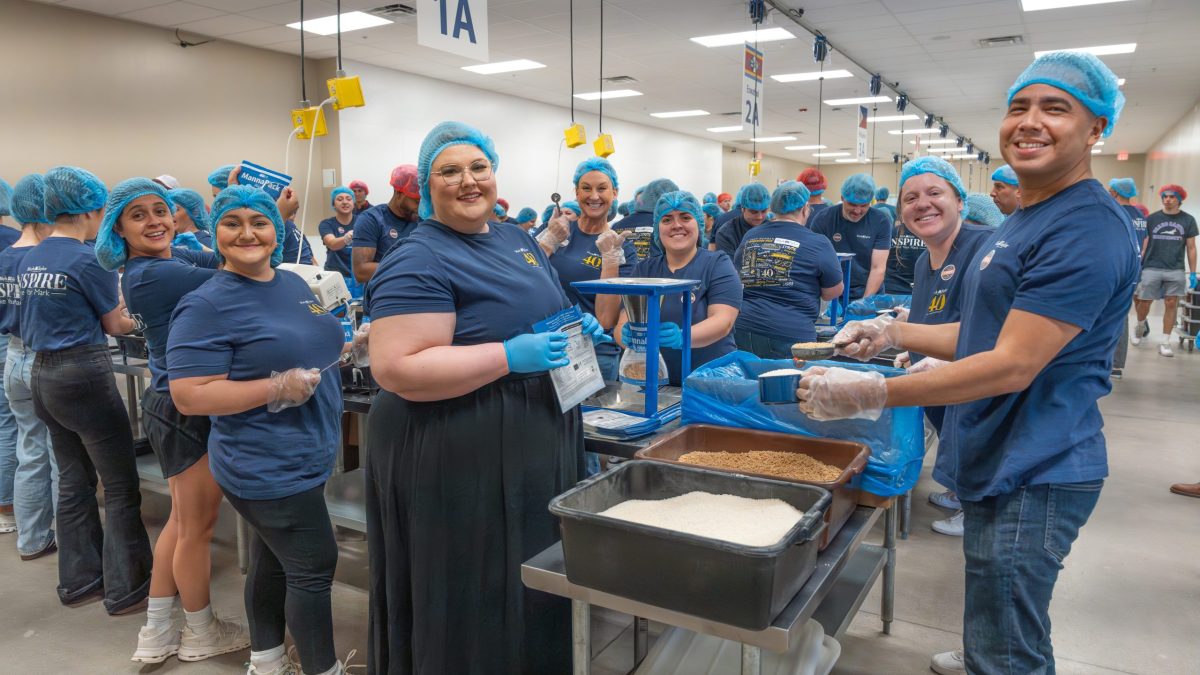 Volunteers from Mark Taylor packing food in assembly line.